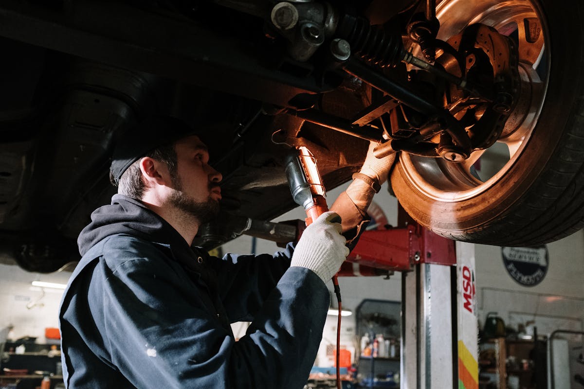 Werkstattmitarbeiter führt Reparatur an Fahrzeugmotor mit Werkzeug aus